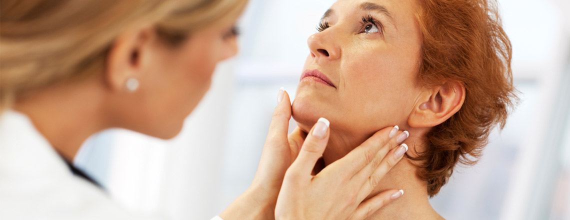 dr checking woman's thyroid on neck