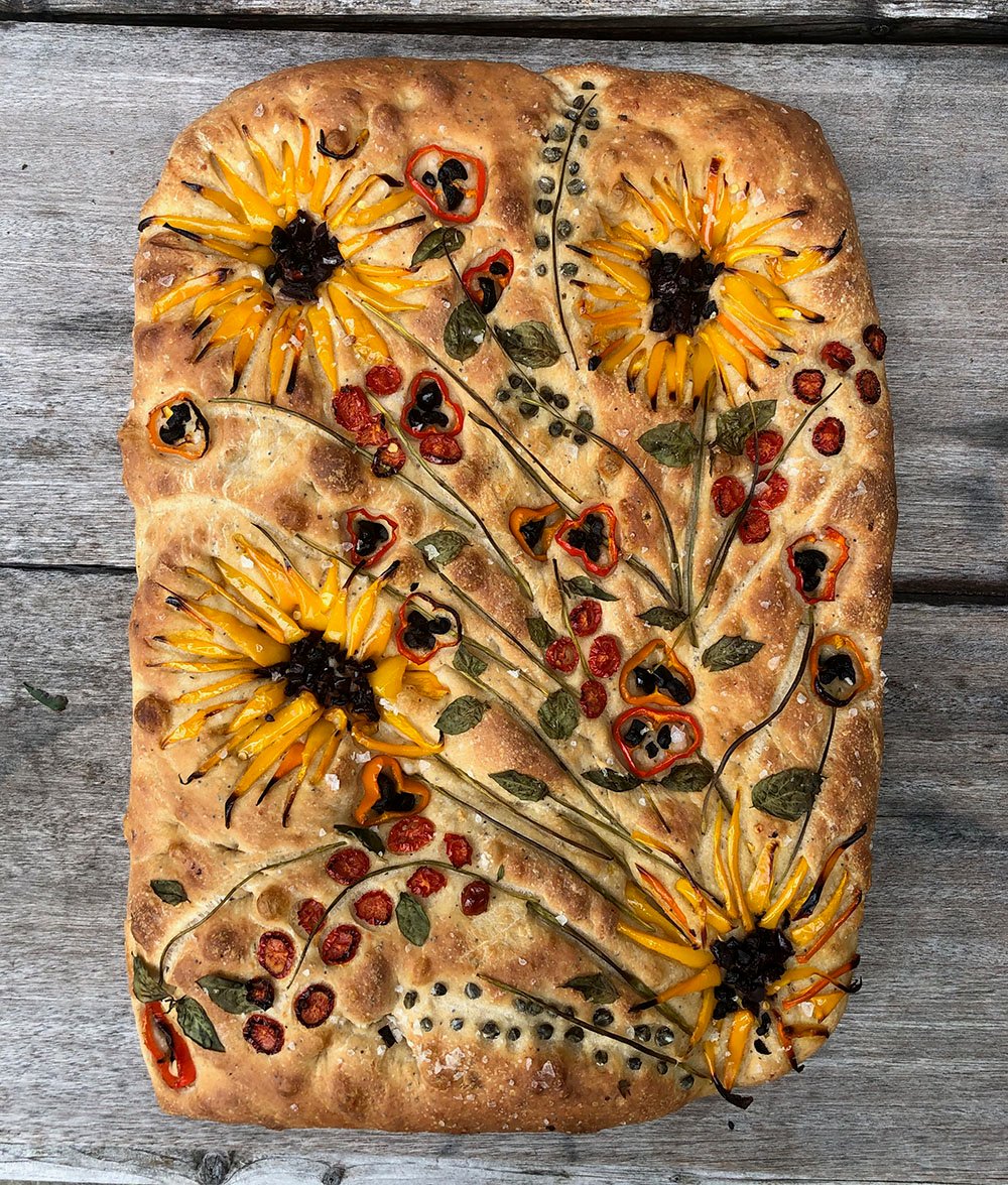 image of focaccia bread with vegetables on top forming an image of sunflowers