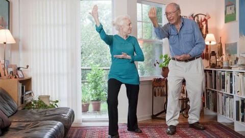 Senior woman and man performing tai chi in their living room