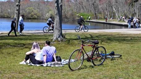 people biking and walking on path around water