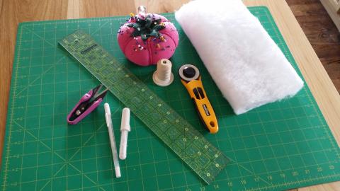 green cutting mat, ruler, batting, scissors, pin cushion